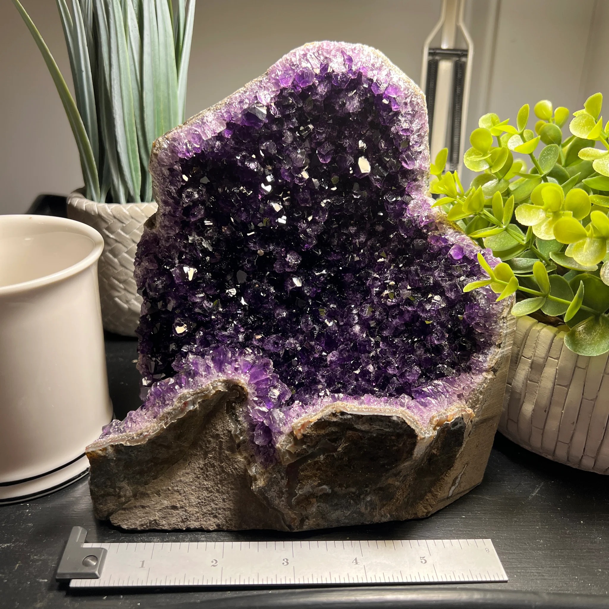 Deep purple amethyst geode cluster on a desk with a 6-inch scale ruler.