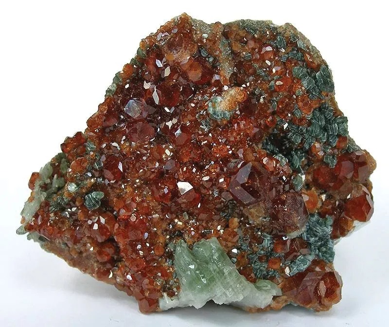 岩石マトリックス中のヘッソナイト・ガーネット（肉桂石）結晶の天然鉱物標本。豊かなシナモンブラウンから濃い赤橙色を呈しています。この未加工のカルシウム・アルミニウム・ケイ酸塩結晶は、宝石本来の有機的で燃えるような結晶習性を示しています。