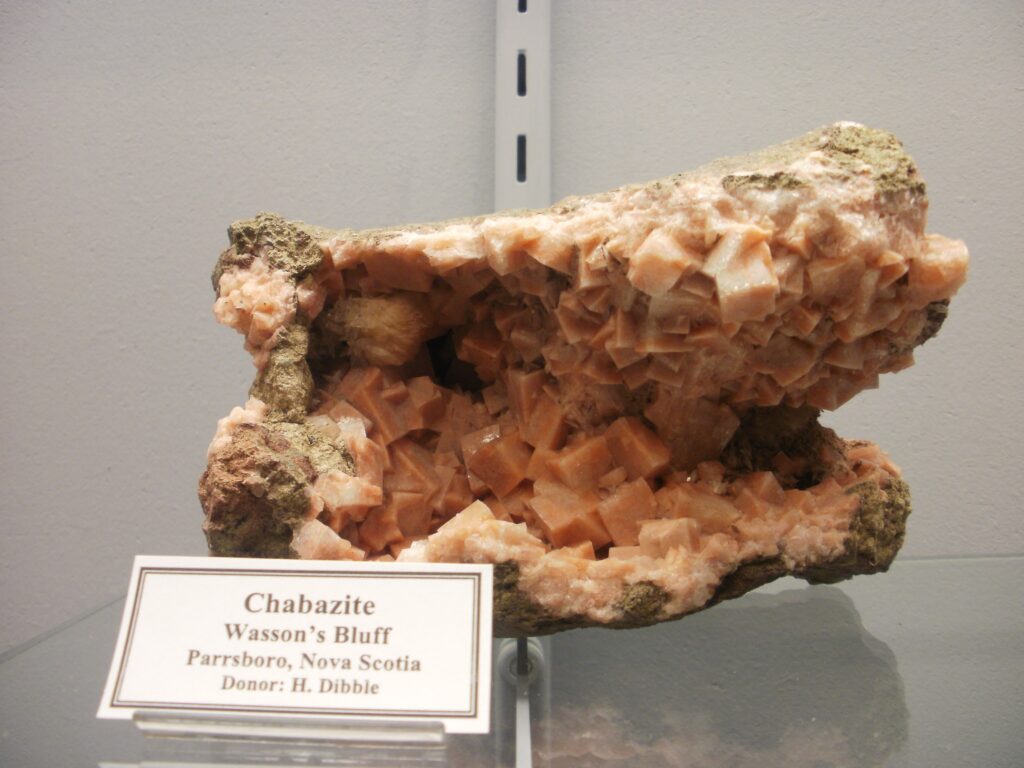 一簇桃粉色的菱沸石晶体,呈菱面体状的“伪立方”晶形,栖息于新斯科舍省瓦森崖玄武岩岩洞的空腔中。