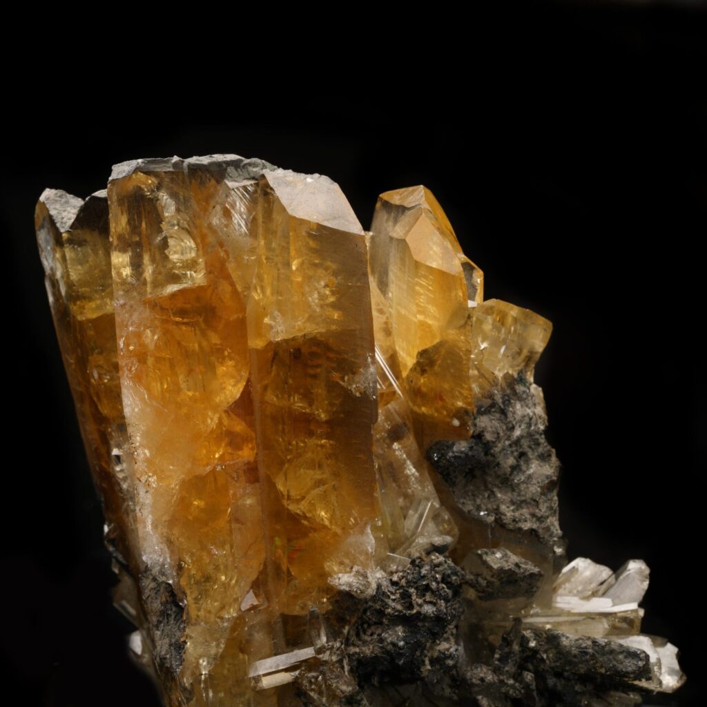 A cluster of vibrant, brownish-orange or amber Anglesite crystals with excellent transparency and well-defined terminations. These deep, earthy tones are a result of specific trace impurities present during the mineral's formation in the lead ore oxidation zone.