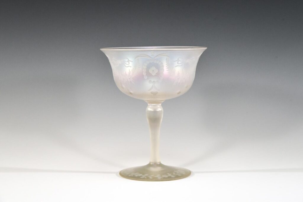 Elegant, etched stemware glass made of Verre de Soie, also known as Silk Glass, exhibiting a delicate, pearlescent iridescent finish and translucent body.