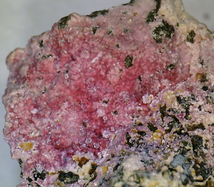 Espécimen mineral de cobaltita que muestra la característica oxidación de eritrita rosa (flor de cobalto) sobre una base metálica oscura.