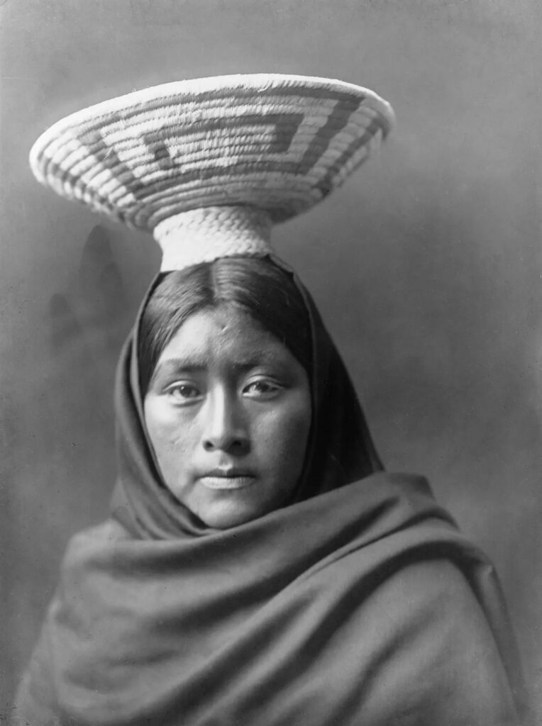 1907年拍摄的一幅肖像画中,一位托霍诺·奥德姆族妇女头顶着精巧编织的篮托盘,披着深色披肩。