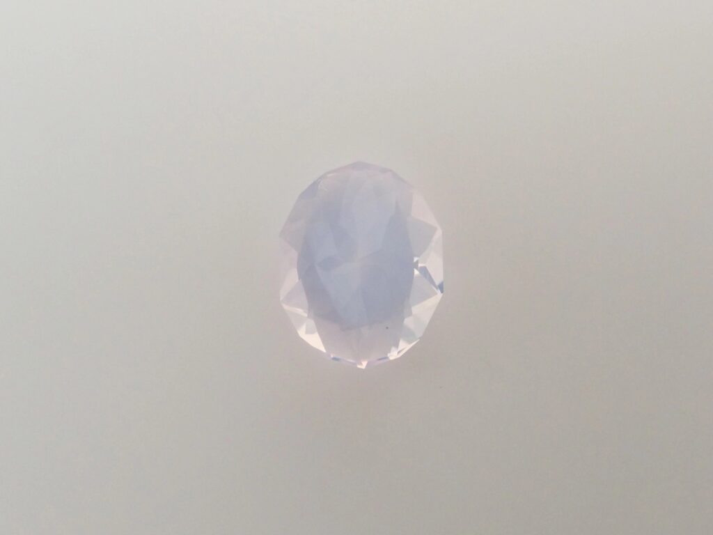 A single, oval-faceted Scorolite stone, exhibiting a delicate, pale lavender-purple hue.