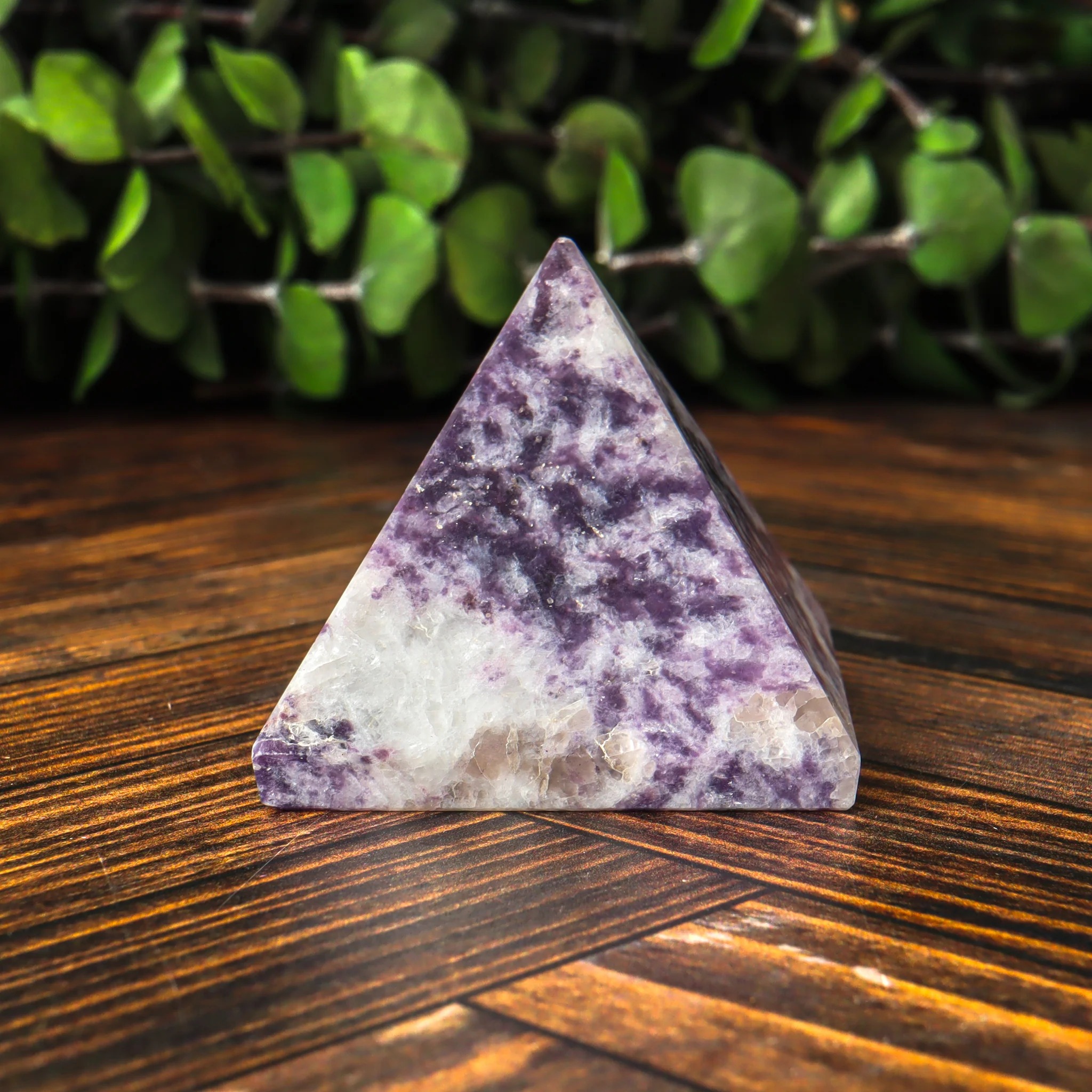 A polished four-sided pyramid made from mottled purple and white lepidolite mica, showcasing its granular crystal structure and distinct lithium-induced lavender and ivory coloring.
