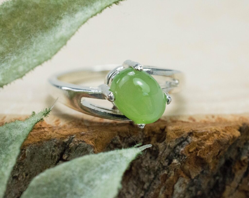 A silver ring featuring an oval green nephrite jade cabochon with a smooth