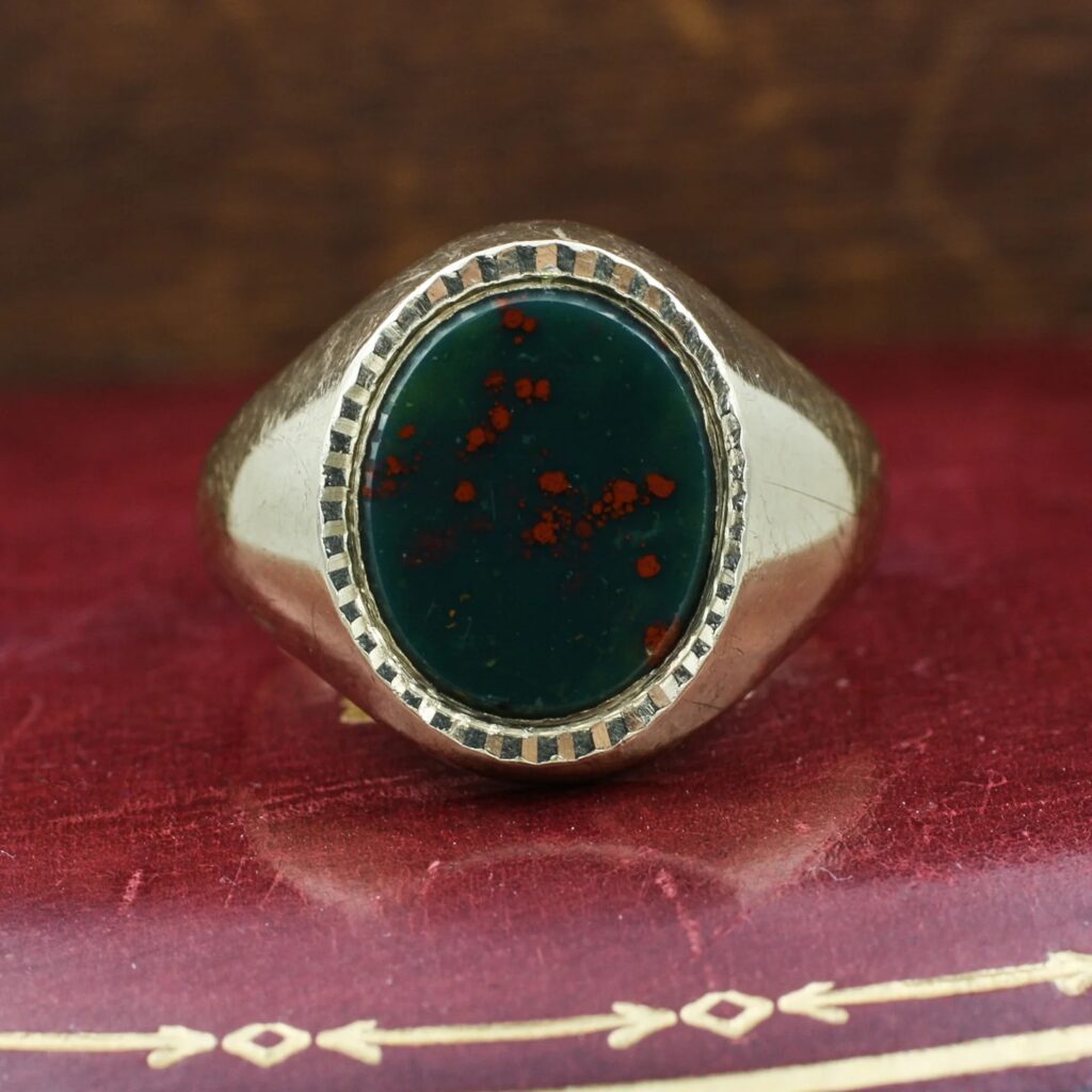 A vintage-style gold signet ring featuring a polished, oval-cut bloodstone cabochon.