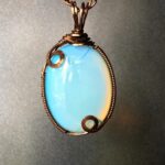 Opalith, wie das Oval, das in diesem Anhänger zu sehen ist, ist ein Glasmaterial, das häufig verwendet wird, um Mondstein zu simulieren.