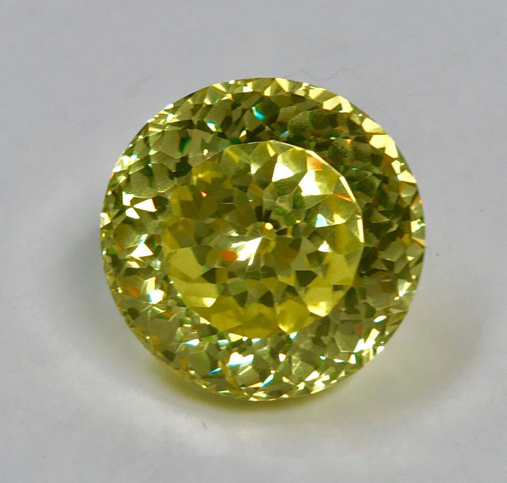 Round-faceted, brilliant yellow lead glass gemstone, displaying intense clarity and high light refraction.
