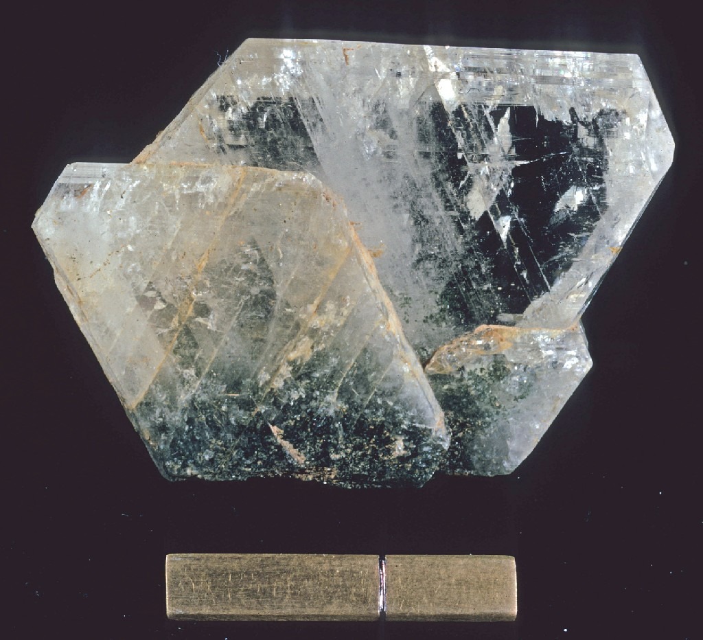 평평하고 칼날 같은 형태와 천연 내부 균열을 보여주는 투명한 조장석 광물 결정.