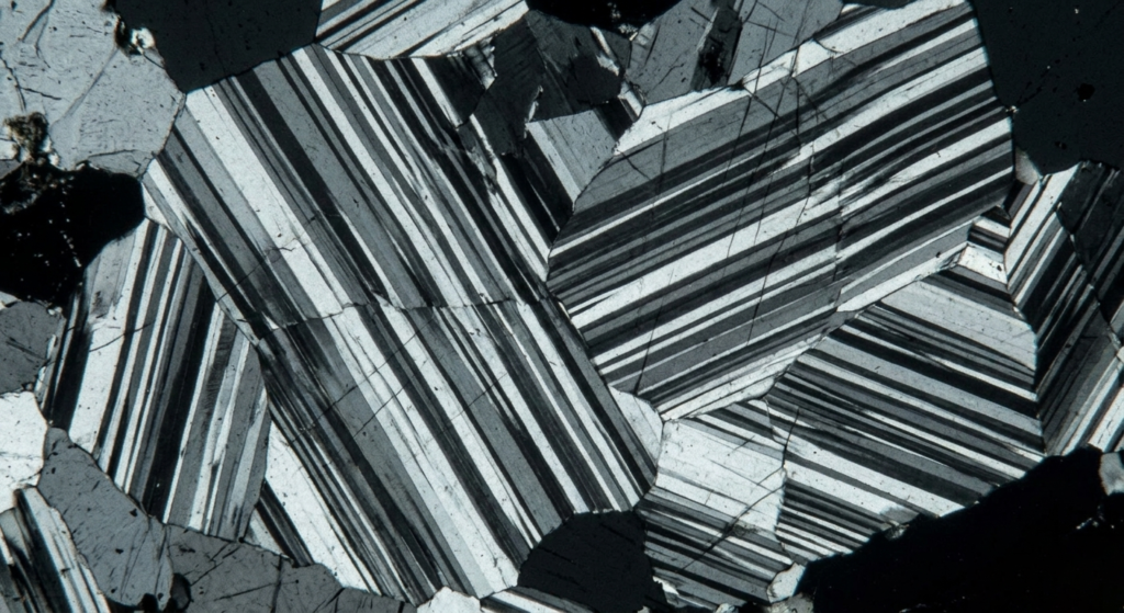 Microscopic view of anorthite showing parallel gray and black stripes known as polysynthetic twinning.