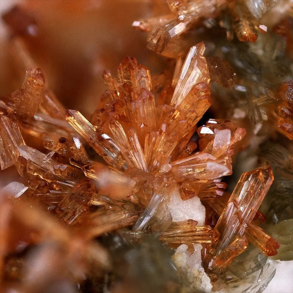 Amas radiés de cristaux d'éosphorite orange et rose brunâtre sur une matrice.