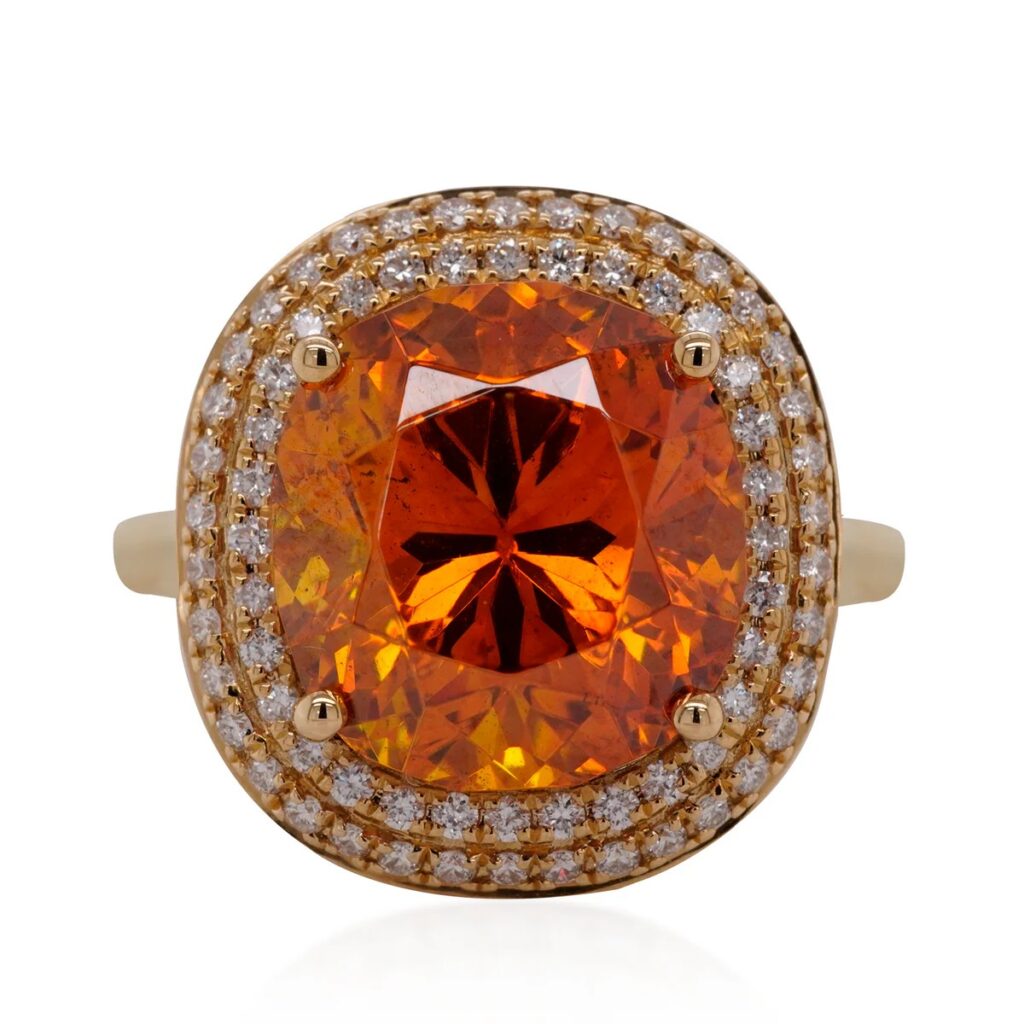 大粒のクッションカット・オレンジスファレライトをセンターに配し、周囲をダブルダイヤモンドパヴェで縁取ったゴールドのヘイローリング。
