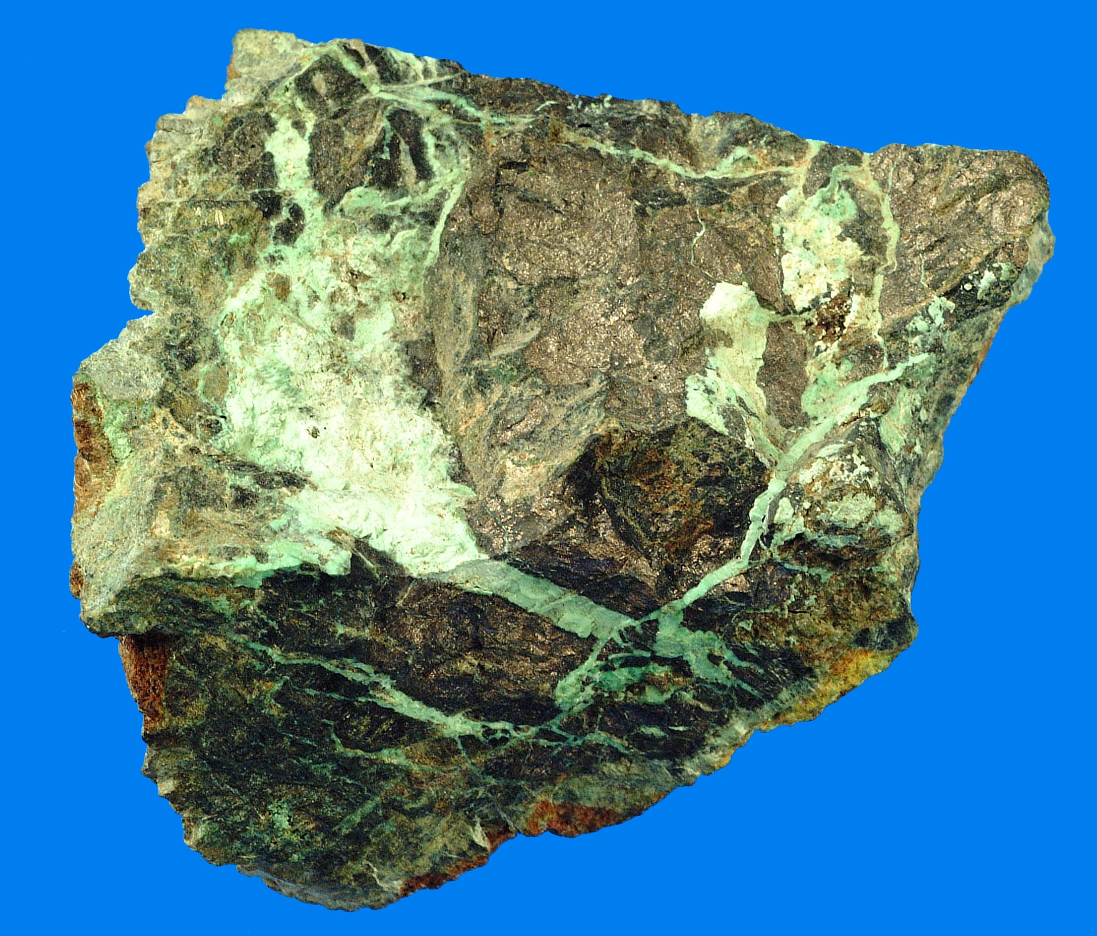 Spesimen mineral Niccolite dengan kerak dan urat oksidasi annabergite hijau sekunder pada permukaan logam.