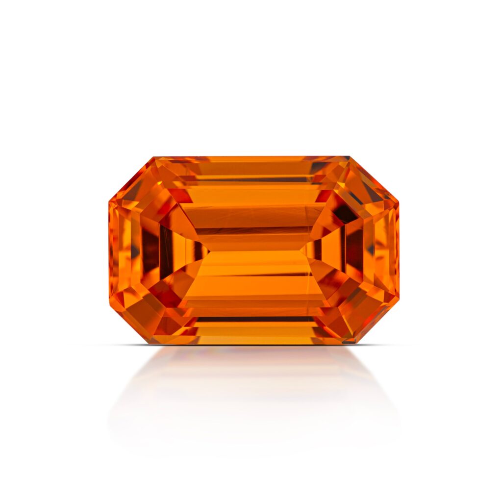 A premium emerald-cut Spessartite Garnet gemstone exhibiting a high-clarity, vibrant "Mandarin" orange hue with excellent light reflection and symmetry.