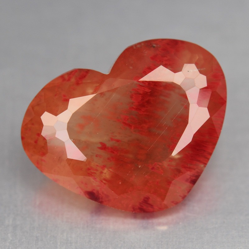 하트 모양으로 커팅된 패싯 안데신 보석으로, 선명한 빨간색과 주황색 색띠가 특징입니다.