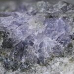 Rohvioletter Iolith-Kristall in einer natürlichen Gesteinsmatrix, der seinen charakteristischen blau-violetten Farbton und seine Kristallstruktur zeigt.