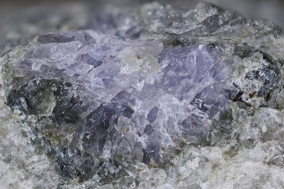 天然岩石基质中的紫色堇青石原石晶体,展示其特有的蓝紫色调和晶体结构。