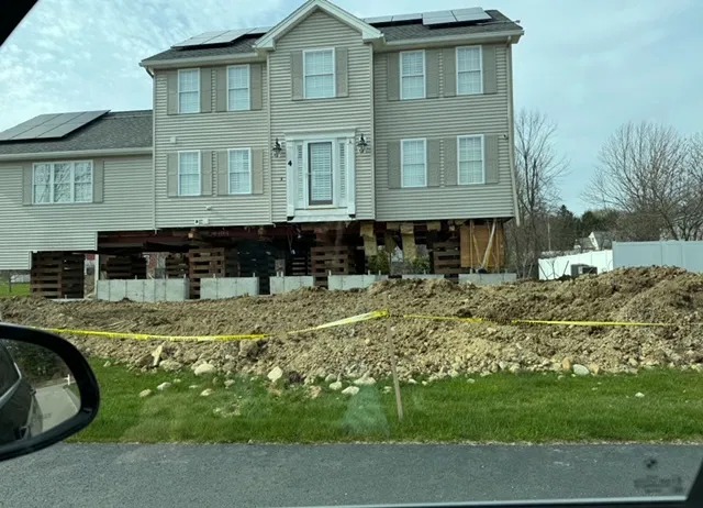 Ein Wohnhaus, das für einen Fundamentaustausch auf Unterbaublöcke und Wagenheber aufgebockt wurde.