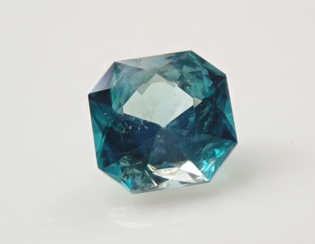 Un espécimen mineral de grandidierita con talla esmeralda u octogonal facetada que muestra el característico pleocroísmo azul verdoso y una alta transparencia.