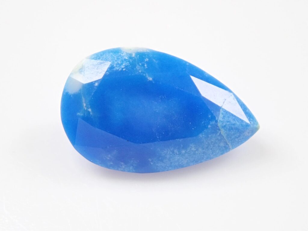 Polierter Ceruleit-Edelstein im Tropfen- oder Birnenschliff, der eine lebendige, leuchtend blaue Farbe mit natürlichen mikrokristallinen Texturen zeigt.