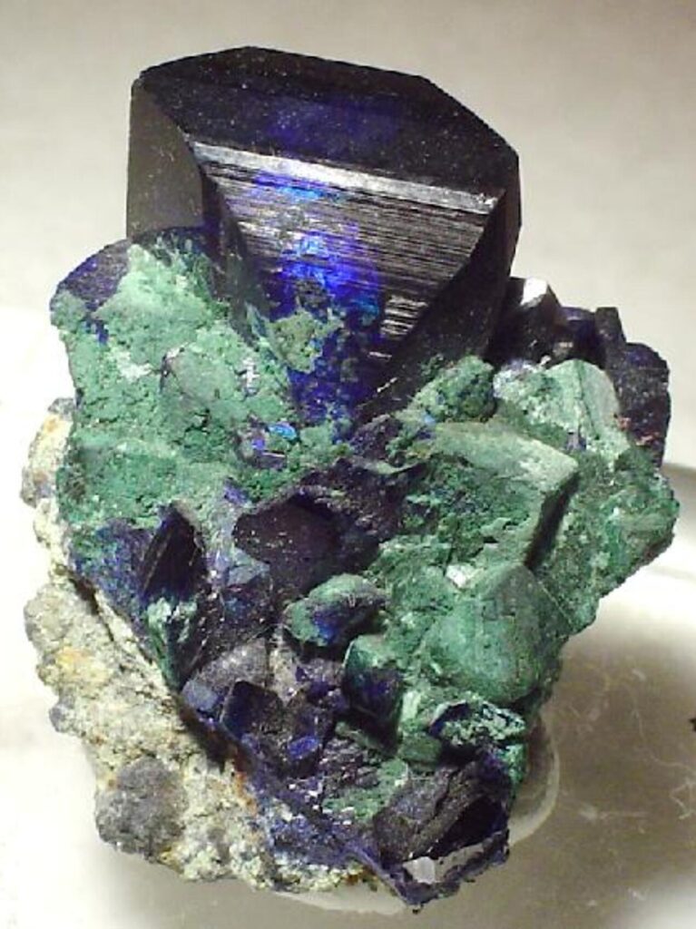 A large prismatic dark blue azurite crystal on green malachite.