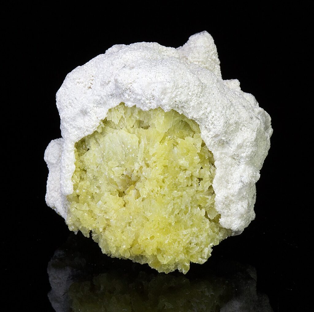 Gugusan mineral alami yang menampilkan inti dari Shortite kristalin yang sebagian terbungkus oleh matriks yang kontras.