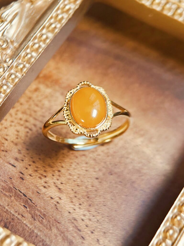 Cincin emas yang menampilkan batu permata mellite cabochon berbentuk oval berwarna kuning madu