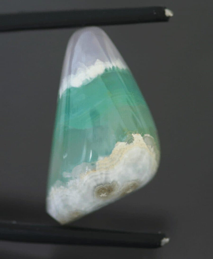 A bi-color pink and medium green-blue smithsonite, divided by a colorless band. 24.40-ct, triangular cabochon, 23.5 x 12.9 mm, Choix, Sinaloa, Mexico.